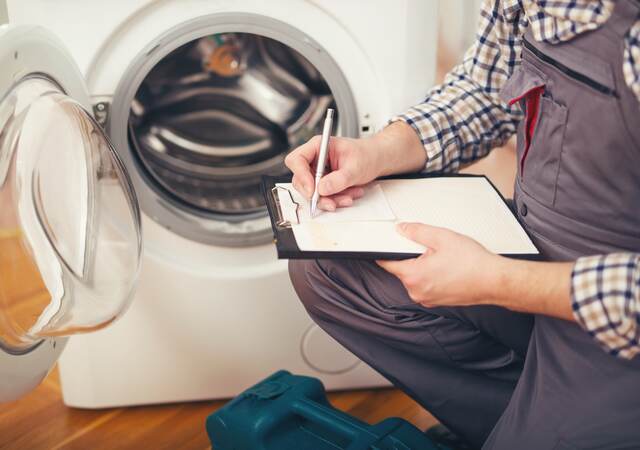 Repairman is repairing a washing machine.